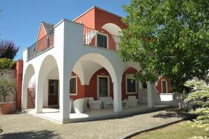 a building with a patio with white furniture and a tree at Relais Casabella in Martina Franca