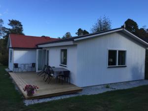 una piccola casa bianca con terrazza in legno di Ljugarn Holiday Home a Ljugarn
