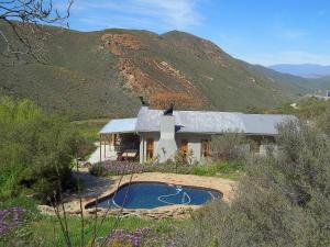 a house with a swimming pool in front of a mountain at Tierhoek Cottages in Robertson