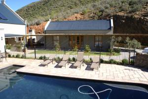 a house with a swimming pool in front of a house at Tierhoek Cottages in Robertson