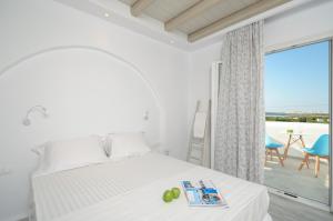 Biała sypialnia z łóżkiem i balkonem w obiekcie Naxian Spirit Suites & Apartments w mieście Agia Anna (Naxos)