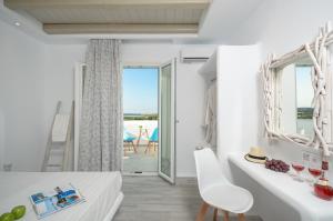 a bedroom with white furniture and a view of the ocean at Naxian Spirit Suites & Apartments in Agia Anna Naxos