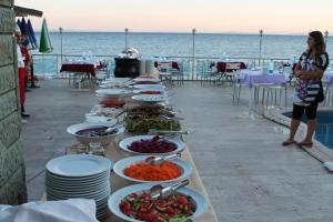 a buffet line with plates of food on a table near the ocean at Ucem Hotel Golden Sea in Altınoluk
