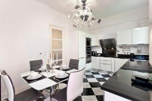 a white kitchen with a dining table and a chandelier at Apartment Saint Philippe 2 in Nice