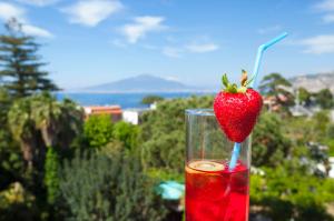 a red drink with a strawberry in a glass at Hotel La Meridiana in Sorrento