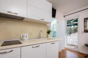- une cuisine avec des placards blancs et un évier dans l'établissement House Coko, à Baška Voda