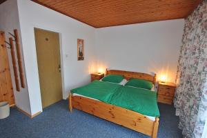 a bedroom with a wooden bed with green sheets at Pension Sybille in Ebensee