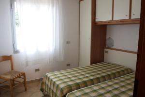 a bedroom with a bed and a chair and a window at Residence Hotel Baia del Sole in Capoliveri