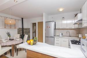 伯德古拉的住宿－Apartments Garmaz，厨房配有白色橱柜和一张带一碗水果的桌子