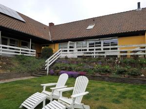 two white chairs sitting on the grass in front of a building at Hammerknuden in Allinge