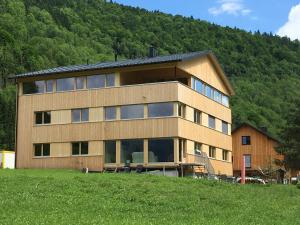 ein Gebäude auf einem Hügel vor einem Berg in der Unterkunft Haus Katharina in Schnepfau