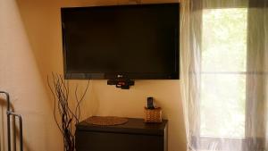 telewizor z płaskim ekranem wiszący na ścianie obok okna w obiekcie Apartament Antique w mieście Karpacz