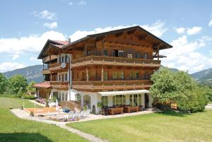 un grand bâtiment en bois avec des chaises dans un champ dans l'établissement Pension Luzenberg, à Auffach