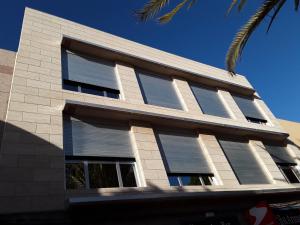 a building with shuttered windows and a palm tree at Viva Cruce de Arinaga in Arinaga