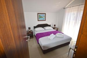 a bedroom with two beds with purple sheets and towels at Apartmani Kovačević in Kotor