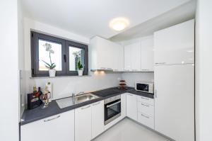 a white kitchen with white cabinets and a sink at Apartments Menalo in Zaton