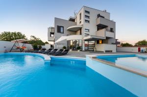 a villa with a swimming pool in front of a building at Apartments Menalo in Zaton