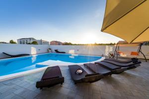 a swimming pool with lounge chairs and an umbrella at Apartments Menalo in Zaton