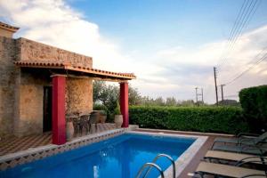 a swimming pool in front of a house at Olympia Villas in Stoupa