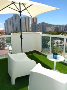 een balkon met witte meubels en een parasol bij Apartamento Cala Finestrat in Benidorm