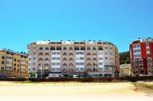 un gran edificio en la playa junto a la arena en Duerming Sea View Viveiro en Viveiro