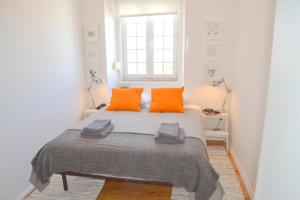 ein Schlafzimmer mit einem Bett mit orangefarbenen Kissen und einem Fenster in der Unterkunft TP MONTE 20, Lisbon Apartment in Lissabon