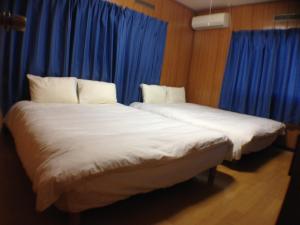 two beds in a room with blue curtains at Family Resort Apartment in Funabashi