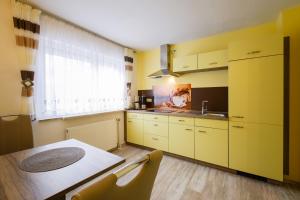 kuchnia z żółtymi szafkami, stołem i oknem w obiekcie Boxis Ferienhaus w mieście Probstzella