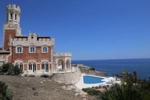 un château au sommet d'une colline avec une piscine dans l'établissement Castello Tafuri, à Portopalo di Capo Passero