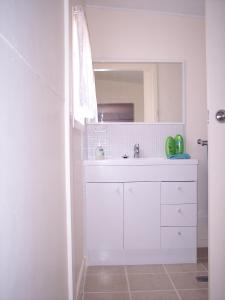 a white bathroom with a sink and a mirror at Browncoat Cottage Mudgee in Mudgee