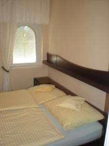 1 dormitorio con 2 camas y ventana en Kentaur Apartmanház en Siófok