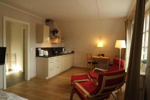 a kitchen with red chairs and a table in it at Appartements Fischerhus in Glowe