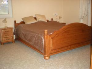 a large wooden bed in a bedroom with a night stand at Kentaur Apartmanház in Siófok