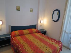 ein Schlafzimmer mit einem Bett mit einer roten und gelben Decke in der Unterkunft Villetta Cenam 37 in Lido delle Nazioni