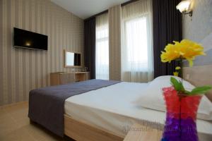 a hotel room with a bed and a vase of flowers at Hotel Greek in Vityazevo