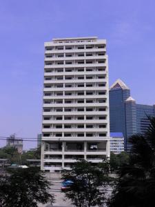 曼谷的住宿－蓬喬克公館酒店，一座高大的白色建筑,在城市前方有树木