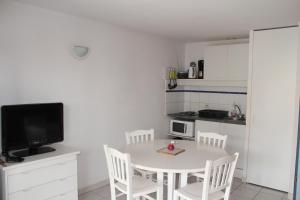 a small kitchen with a white table and chairs at Residence Le Grand Bleu in Vendres