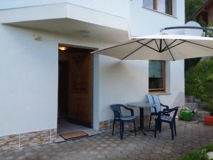 eine Terrasse mit einem Tisch, Stühlen und einem Sonnenschirm in der Unterkunft Ferienwohnung Schlemmer in Doren
