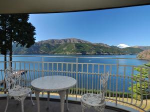 a table and chairs on a balcony with a view of a lake at The Prince Hakone Lake Ashinoko in Hakone
