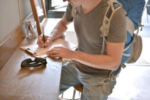 a man sitting at a table with a pair of scissors at Chillulu Hostel in Yokohama