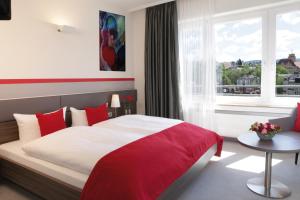 Schlafzimmer mit einem roten und weißen Bett und einem Fenster in der Unterkunft Hotel am Markt in Baden-Baden