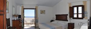 a bedroom with a bed and a balcony with the ocean at Hotel Resort Nuraghe Arvu in Cala Gonone