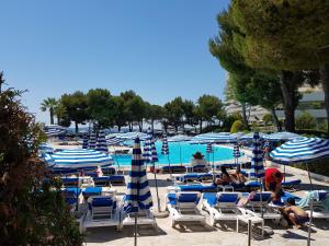 a pool with blue and white chairs and umbrellas at Apartments at Commodoro in Villeneuve-Loubet