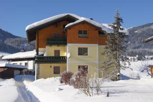 a building with snow on the ground in front of it at Ferienhaus Reiter Lotte in Gosau