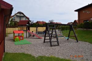 um parque infantil com dois baloiços e um escorrega em Aga domki letniskowe em Rewal
