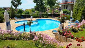 a swimming pool in a yard with flowers at Delfin Port Apartments - Prime Location & Parking & Pet Friendly in Sveti Vlas