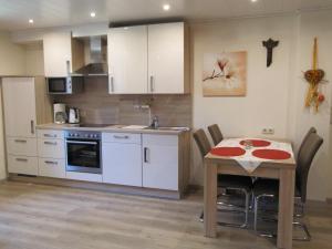 a kitchen with a table and a kitchen with white cabinets at Abendstille am Obstgarten mit Terrasse in Zapfendorf