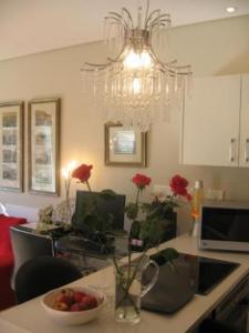 a kitchen with a table with a bowl of fruit and a chandelier at Navona Constantia Guest Cottage in Cape Town