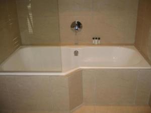 a white tub in a bathroom with a shower at Navona Constantia Guest Cottage in Cape Town