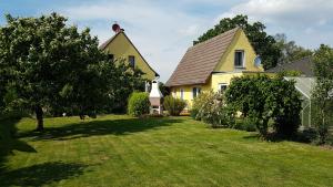 ein gelbes Haus mit einem großen Garten mit Bäumen in der Unterkunft Ferienhaus Sonneck in Klockenhagen